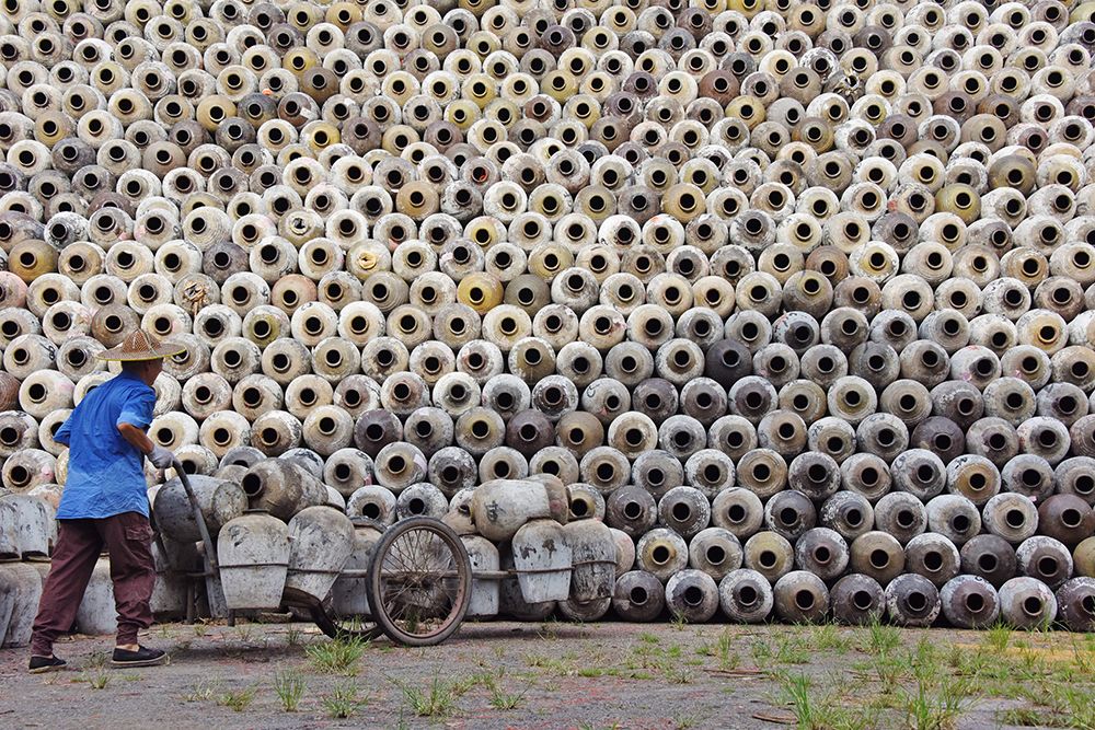 Man pushing cart loaded with wine jars to the big pile in a winery-Zhejiang Province-China